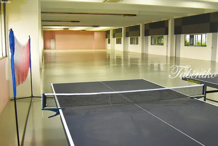 Spacious indoor sports hall with polished concrete floors, featuring a table tennis table and badminton net setup.