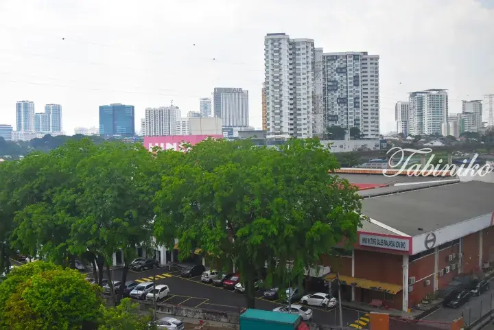 Urban view of Kuala Lumpur showing Hino Motors dealership, tall residential towers, and the AIA building in the background.