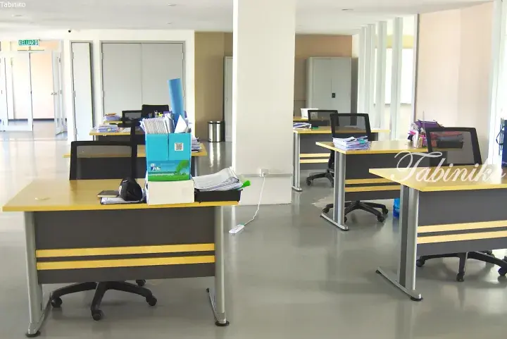 Modern office interior with yellow and grey desks, black mesh chairs, and document boxes in a bright workspace.