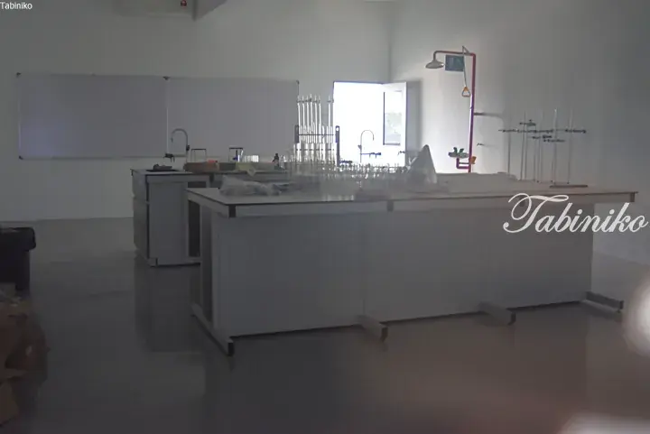 Modern science laboratory with white workbenches, glassware, and safety equipment in a bright room.