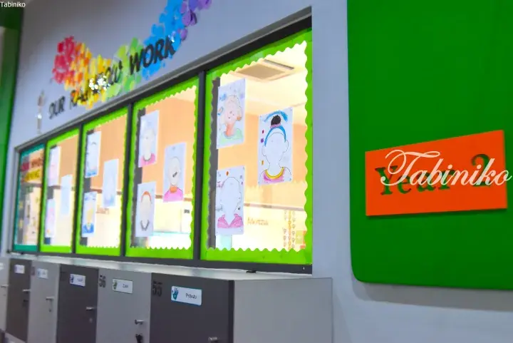 Bright classroom display with student drawings and lockers labeled with names like Pranav and Zack.