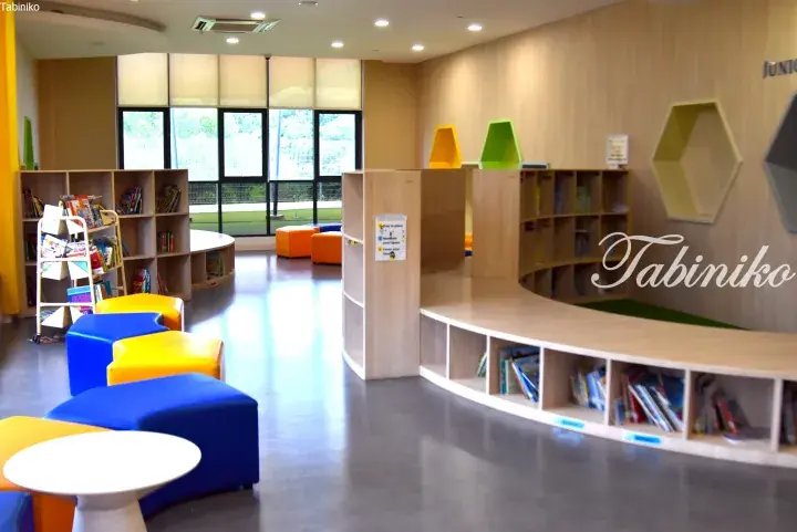 Bright children’s library with colorful modular seating, wooden bookshelves, and hexagonal wall displays.