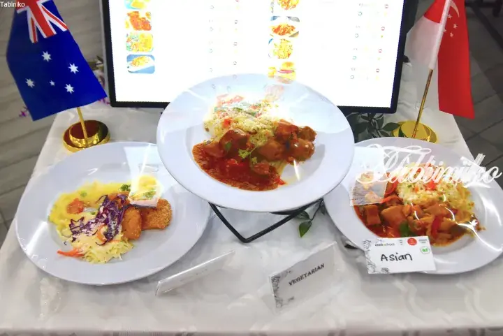 Three plated meals displayed on a table with Australian and Singaporean flags, labeled Vegetarian and Asian.