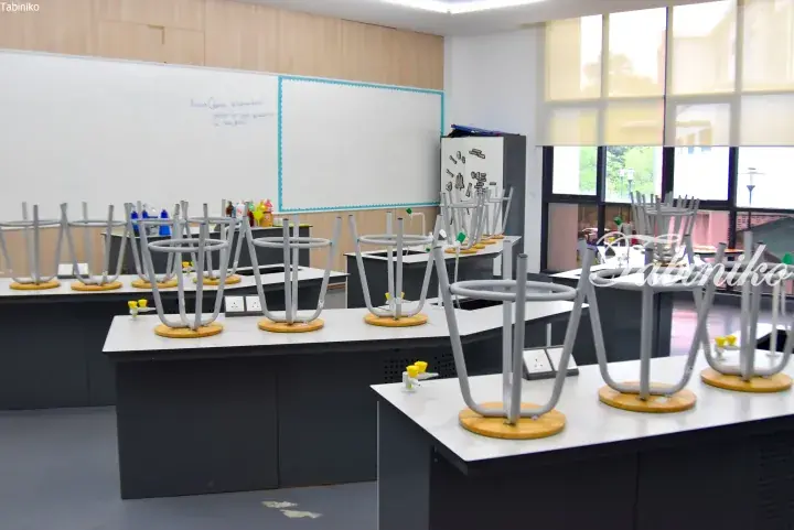 Modern science laboratory with stools stacked upside down on lab benches and a whiteboard with research questions.