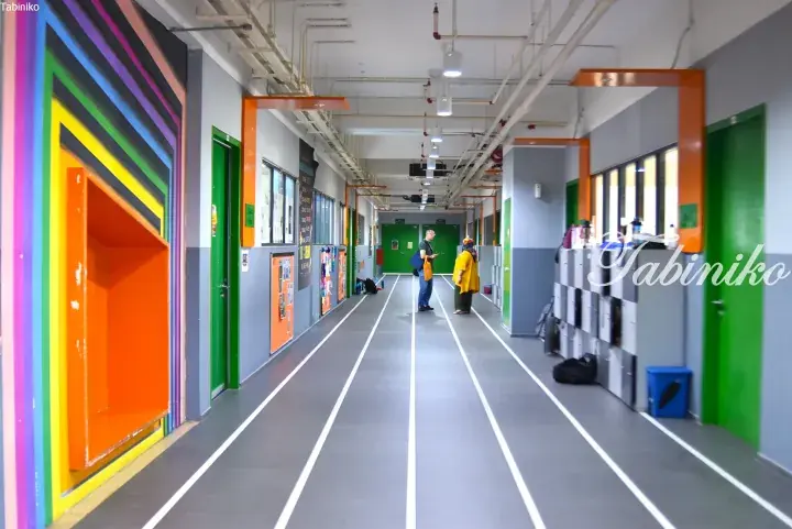 Colorful hallway with rainbow wall art and floor tracks at a modern Malaysian school.