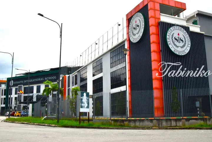 Modern building exterior of Straits International School featuring orange accents and large circular SIS logos.