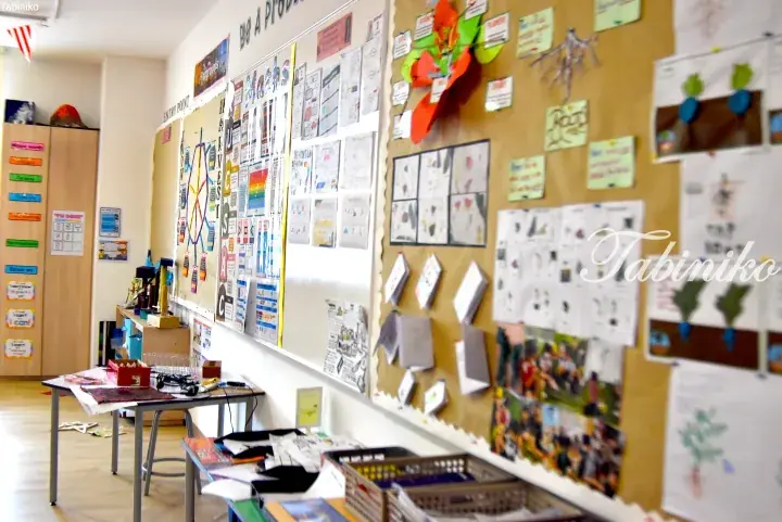 Classroom wall displays student projects, math charts, and colorful decorations in a bright learning space.