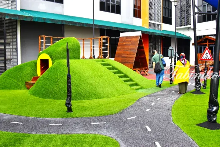 Modern playground with green artificial turf hill and wooden climbing structure at a property.
