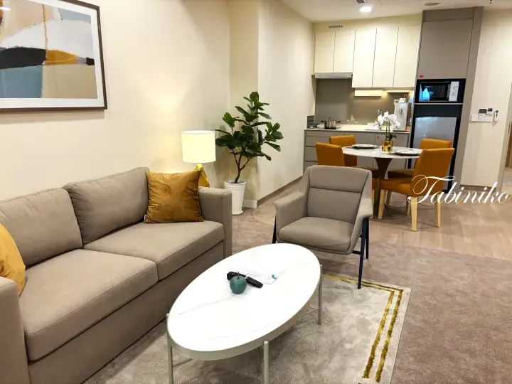 Modern furnished apartment interior with beige sofa, dining area, and kitchen in Kuala Lumpur