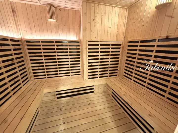 Interior of a modern wooden sauna with tiered benches and slatted walls for relaxation.