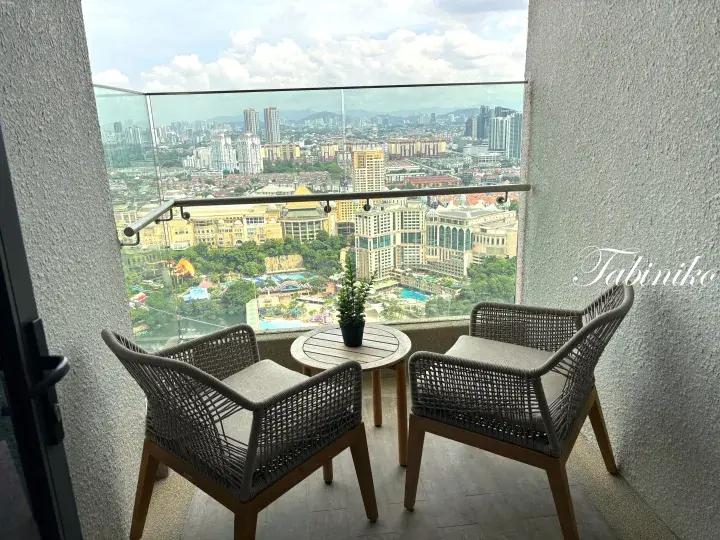 Balcony with wicker chairs overlooking the city skyline and Sunway Lagoon theme park in Malaysia.