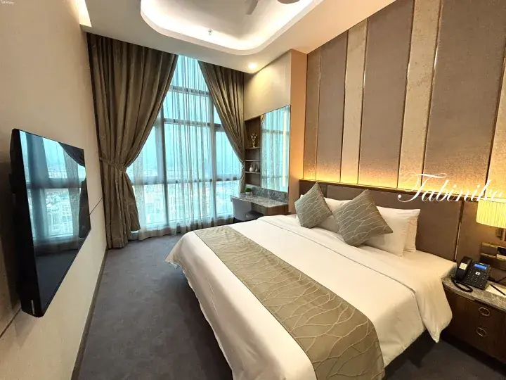 Modern hotel room with a king bed, city view window, and wall-mounted TV in Kuala Lumpur