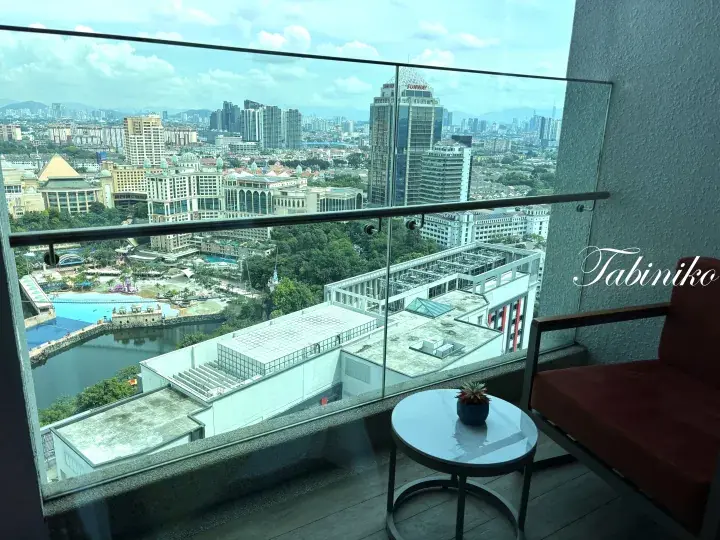 View from a balcony overlooking Kuala Lumpur’s cityscape, featuring a water park and modern buildings.