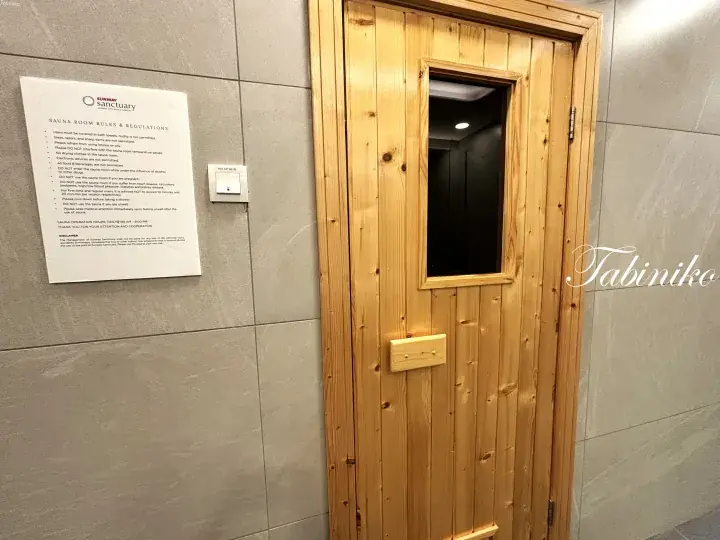Wooden sauna door with glass window and rules sign at Sanctuary Spa in Malaysia.