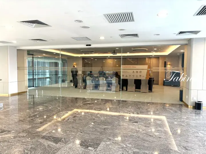 Modern office lobby with polished marble floors and glass walls leading to a conference room labeled Harmony Hall.