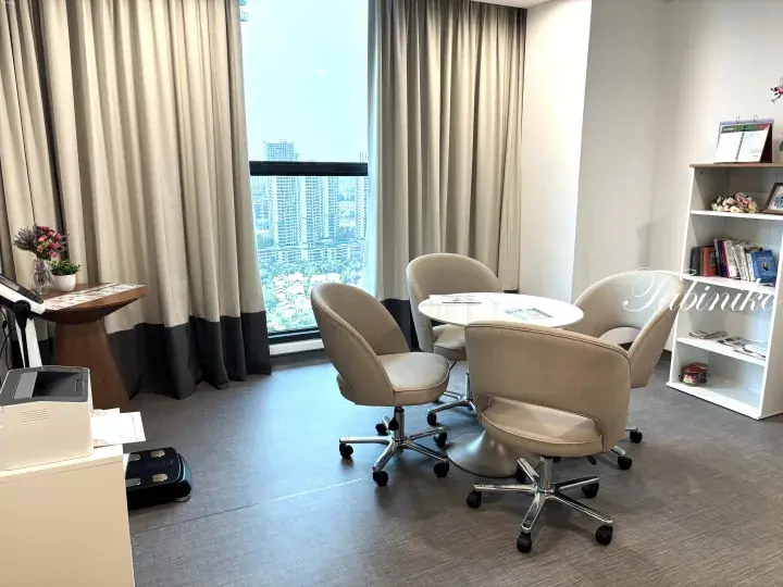 Modern consultation room with beige chairs, a round table, and a city view window in a Malaysian property.