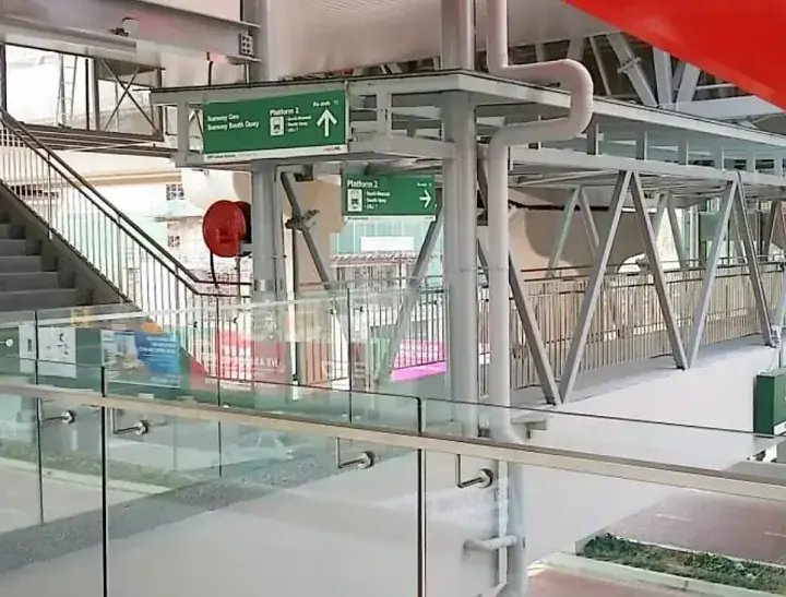 Green directional signs at a modern Malaysian transit station guide passengers to platforms and exits.