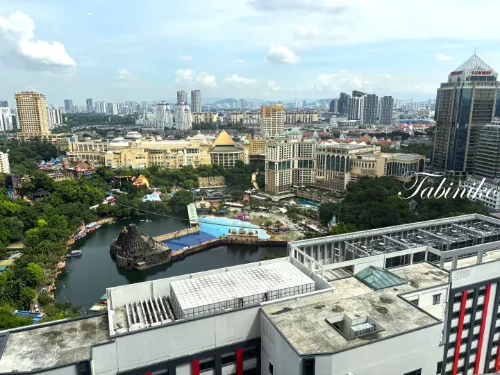Aerial view of Sunway Lagoon theme park and water park surrounded by lush greenery and the Kuala Lumpur skyline.
