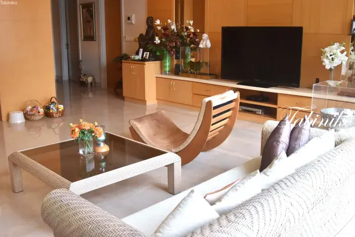 Spacious modern living room with wooden furniture, a curved lounge chair, and a flat-screen TV in a luxury property.