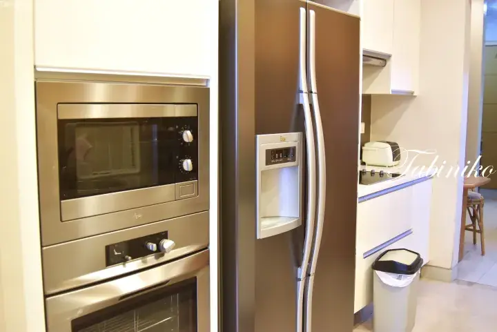 Modern kitchen featuring a stainless steel side-by-side refrigerator with water dispenser and built-in microwave oven.