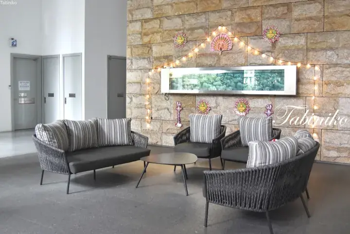 Cozy lounge area with modern wicker furniture and festive Diwali decorations on a stone wall.