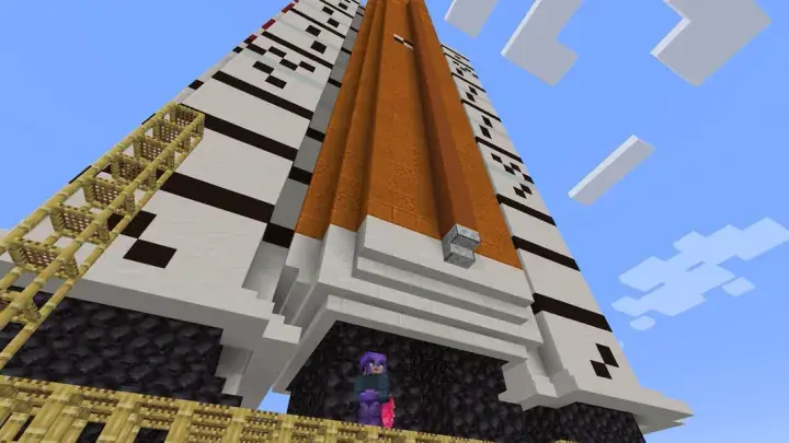 Low-angle view of a Minecraft tower with bamboo scaffolding and a player character at the base.