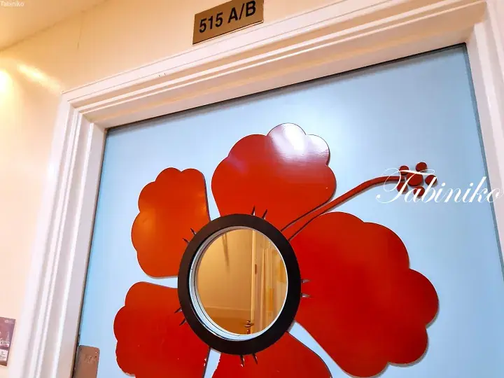 Blue hotel room door 515 A/B featuring a large red flower design with a circular peephole.