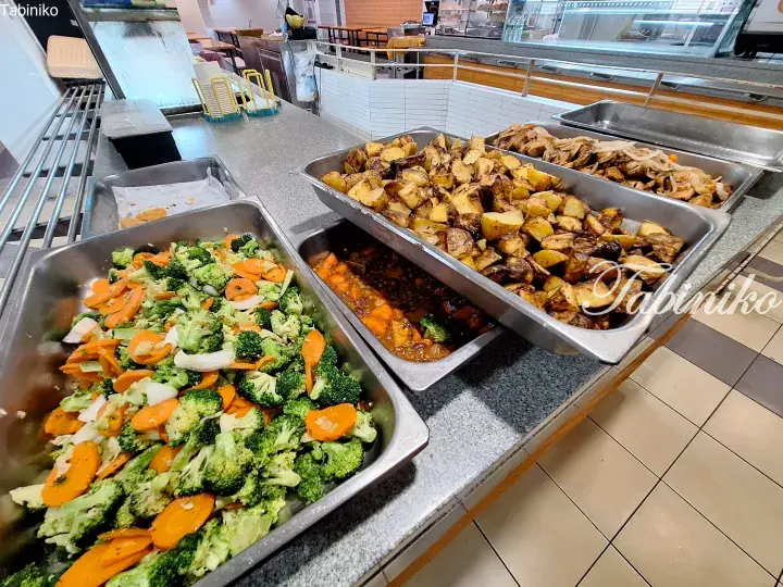 Buffet trays of roasted potatoes, stir-fried broccoli and carrots, and stewed meat at a Malaysian restaurant.