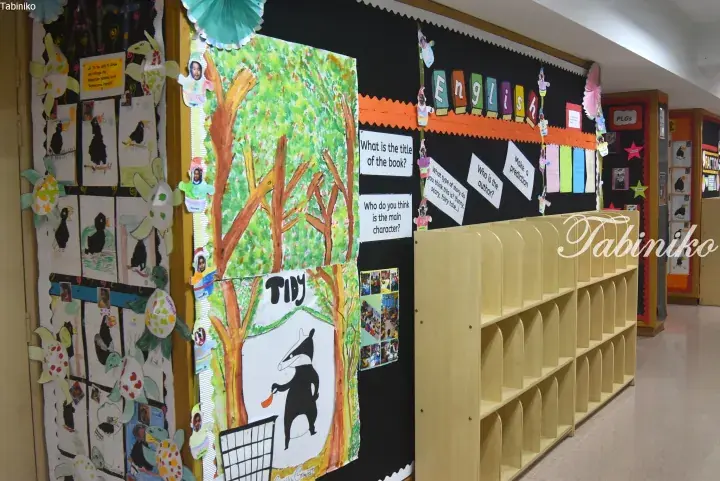 Classroom display board featuring a children’s book illustration of a badger named Tidy, surrounded by student artwork and English learning prompts.
