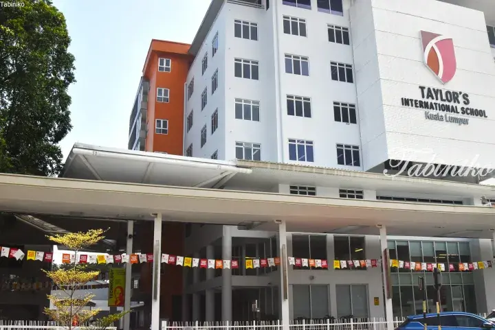 Exterior of Taylor’s International School Kuala Lumpur featuring a white facade, orange accents, and colorful banners.