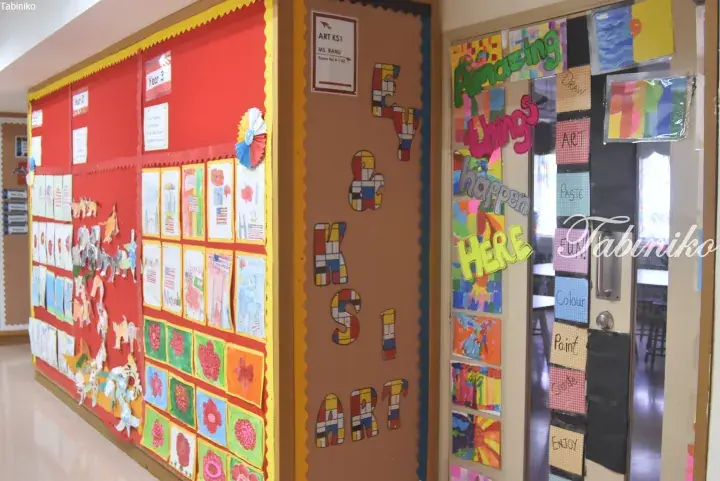 Colorful KS1 Art classroom display board featuring student artwork and a door with ‘Amazing things happen here’ sign.