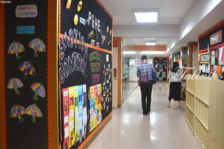 School hallway with bulletin boards on emotion control and mental health, featuring colorful displays and students walking.
