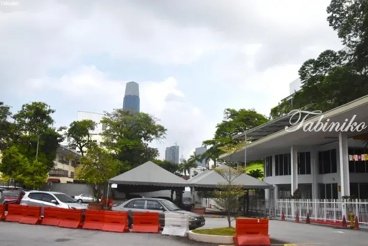 View of Merdeka 118 skyscraper from a parking lot with tents and orange barriers in Kuala Lumpur.