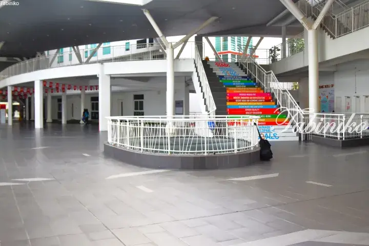 Colorful staircase displaying UN Sustainable Development Goals inside a modern building with white pillars and grey flooring.