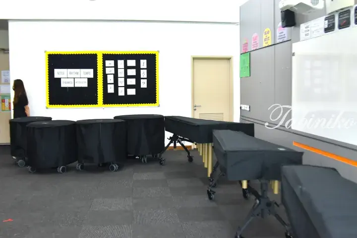Music classroom with covered timpani and xylophones, musical notation bulletin board, and whiteboard.