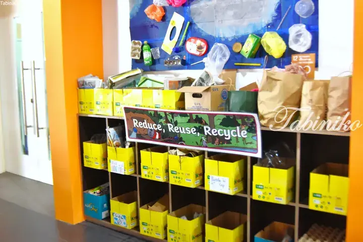 Recycling station with yellow bins and a ‘Reduce, Reuse, Recycle’ sign in a Malaysian property.