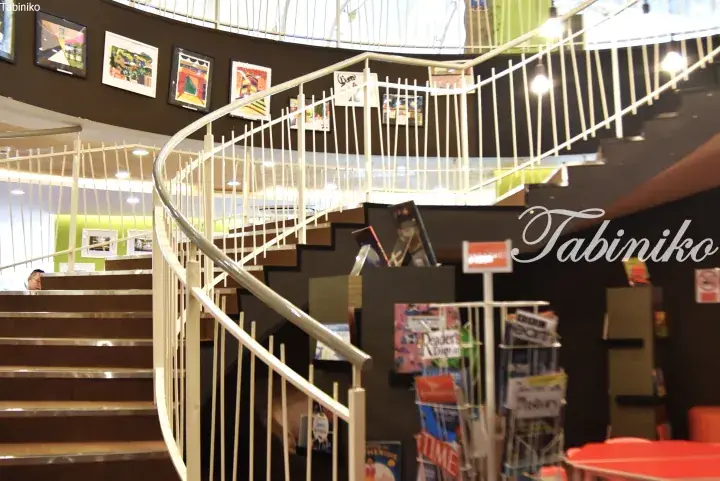 Spiral staircase with white railings and framed artwork in a modern library or study area.