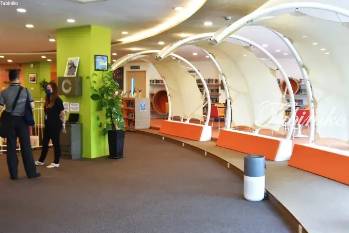 Modern library interior with curved white reading pods, orange seating, and bright green accent walls.