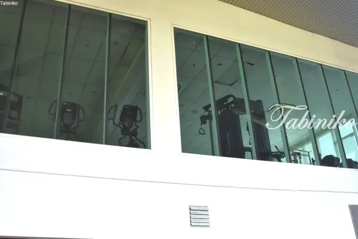 Gym equipment visible through large glass windows of a modern building.