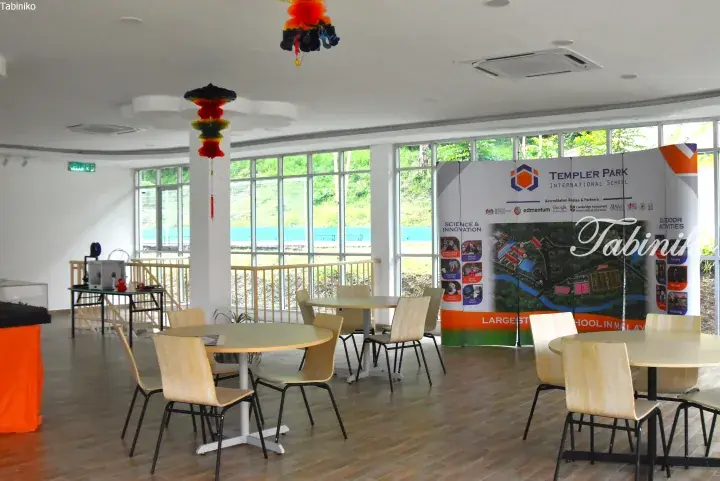 Bright dining area at Templar Park International School with round tables, chairs, and a large promotional banner.