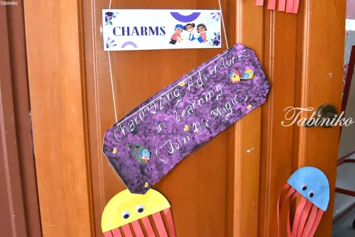 Classroom door decorated with a purple sign reading “Charmazing Adventures in Learning” and colorful paper jellyfish crafts.