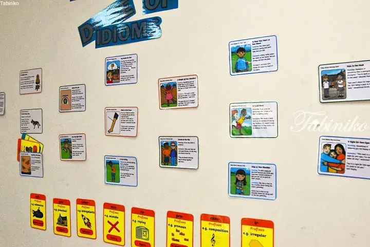 Classroom wall display featuring English idioms and prefixes with colorful educational cards and illustrations.