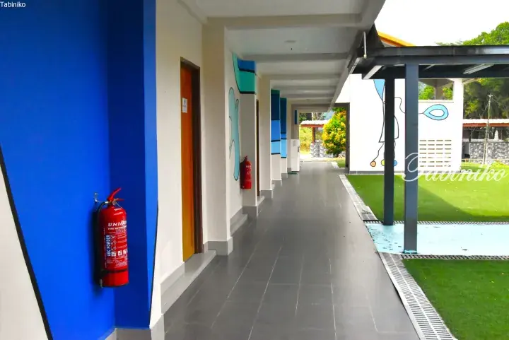 Covered walkway with blue pillars and fire extinguishers at a modern property in Malaysia.