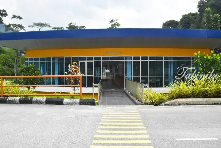 Modern building with blue and yellow facade, glass windows, and a wheelchair ramp entrance.
