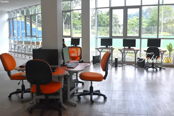 Modern computer lab with orange chairs and large windows overlooking a sports court