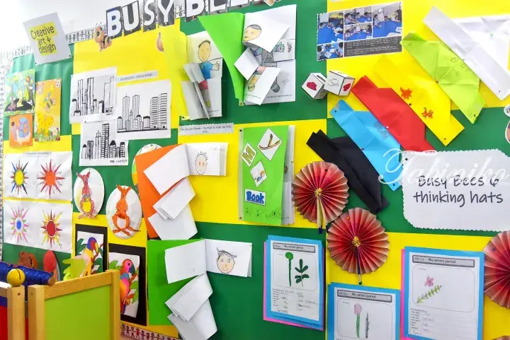 Colorful classroom bulletin board displaying children&rsquo;s art, flipbooks, and origami with a &lsquo;Busy Bees&rsquo; theme.