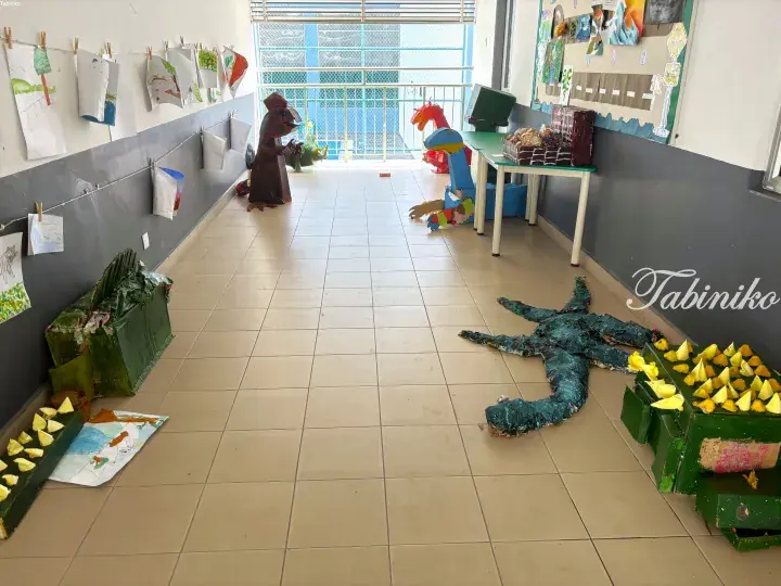 Colorful handmade cardboard animal figures and children’s drawings displayed in a school corridor.