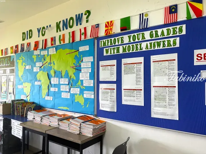 Classroom bulletin boards displaying a world map with facts and model exam answers to improve grades.