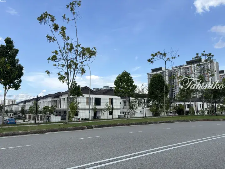 Modern white terrace houses with dark roofs behind a fence, set against a backdrop of high-rise apartments under a blue sky.