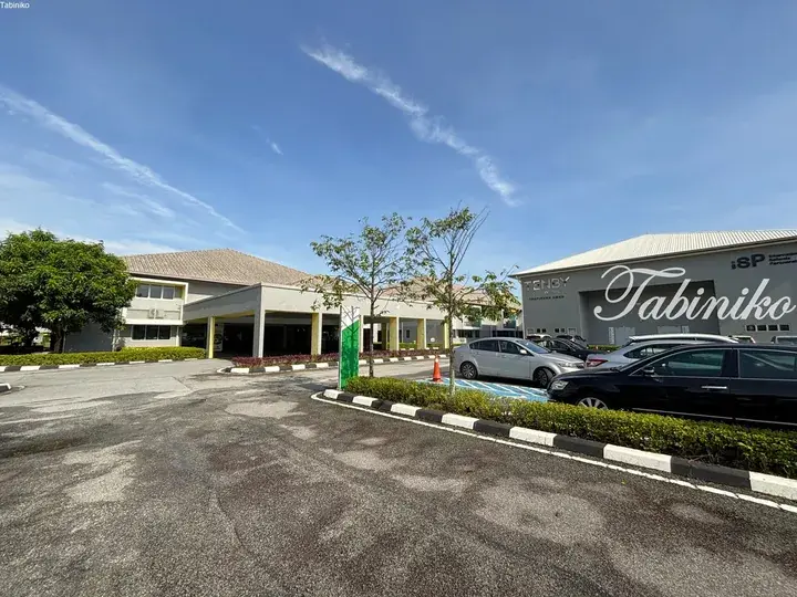Tenby Schools Tropika Hills campus exterior with parking lot and modern buildings under a blue sky.